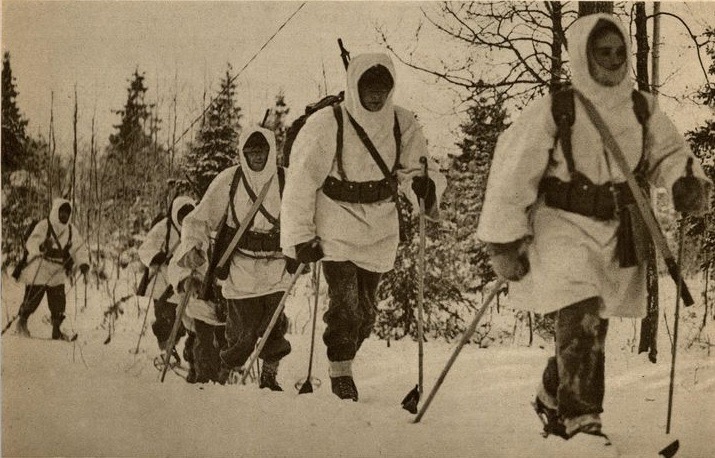 A Swedish Volunteer Corps patrol in white snow suits skiing through the forest on the Salla front, 1940
